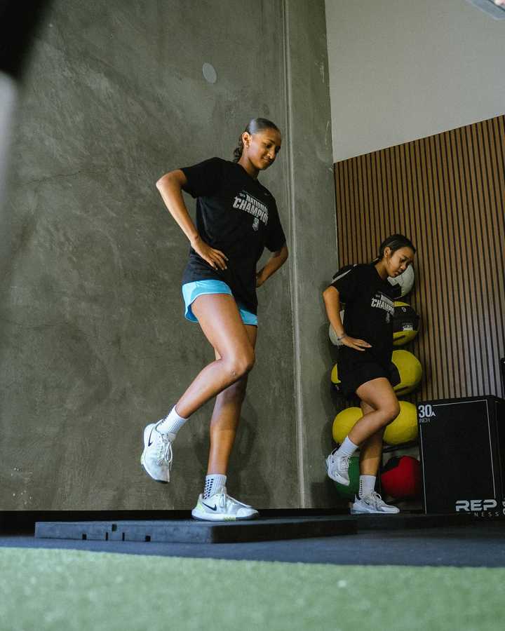 Athlete balancing on one leg during a movement assessment while a coach watches
