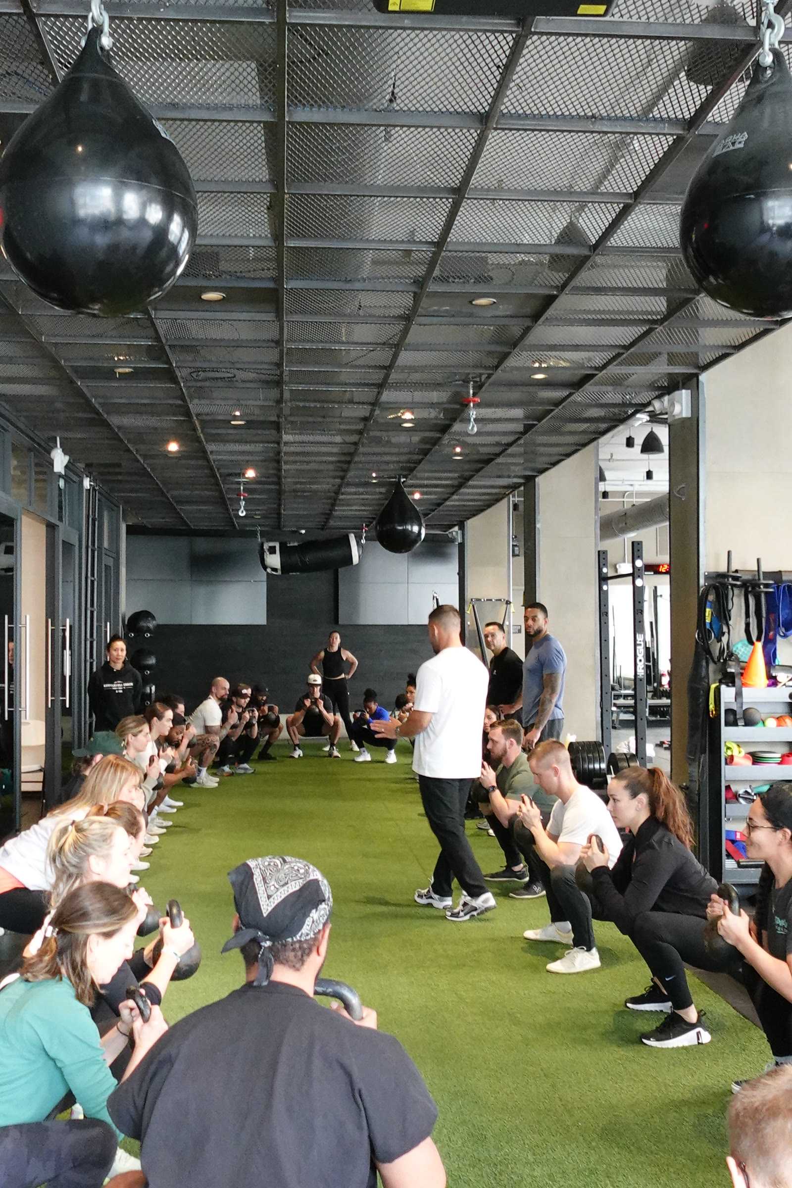 Hunter Crine coaching a turf-floor kettlebell session with workshop attendees working in two rows